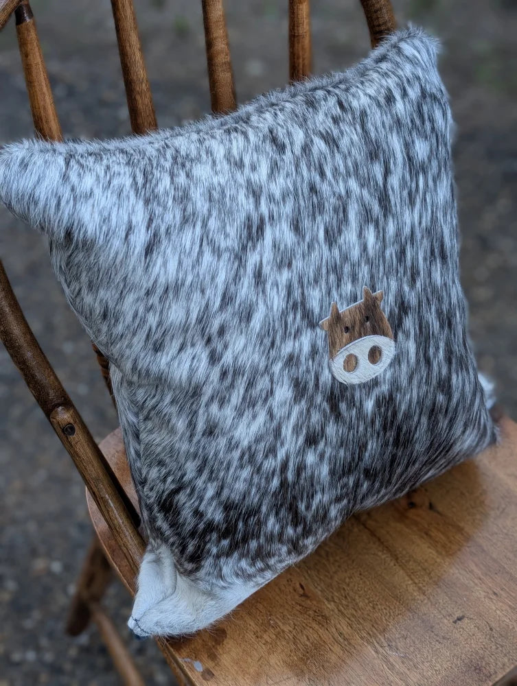 Gray and white speckled double sided cowhide cushion with wooden mini moo double cow face appliqué