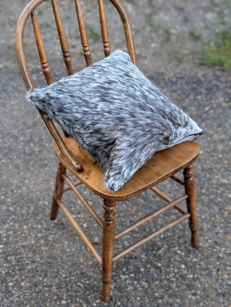 Gray and white double sided cowhide cushion mini moo with soft textured surface resting on wooden chair
