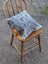 Gray and white double sided cowhide cushion mini moo with soft textured surface resting on wooden chair