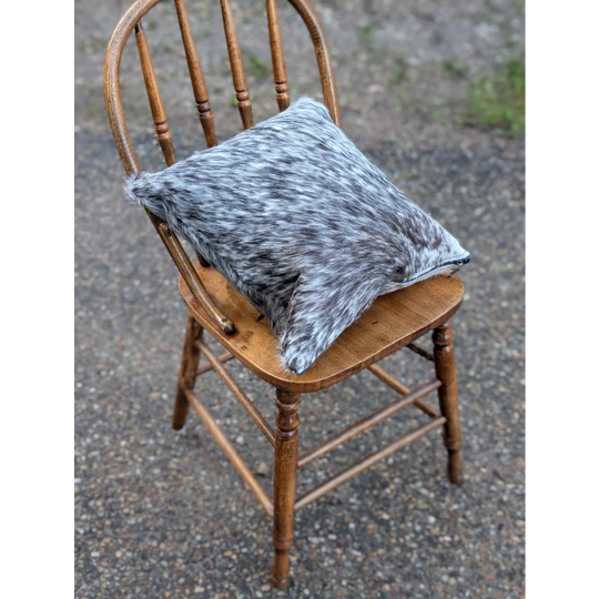 Gray and white double sided cowhide cushion mini moo with soft textured surface resting on wooden chair