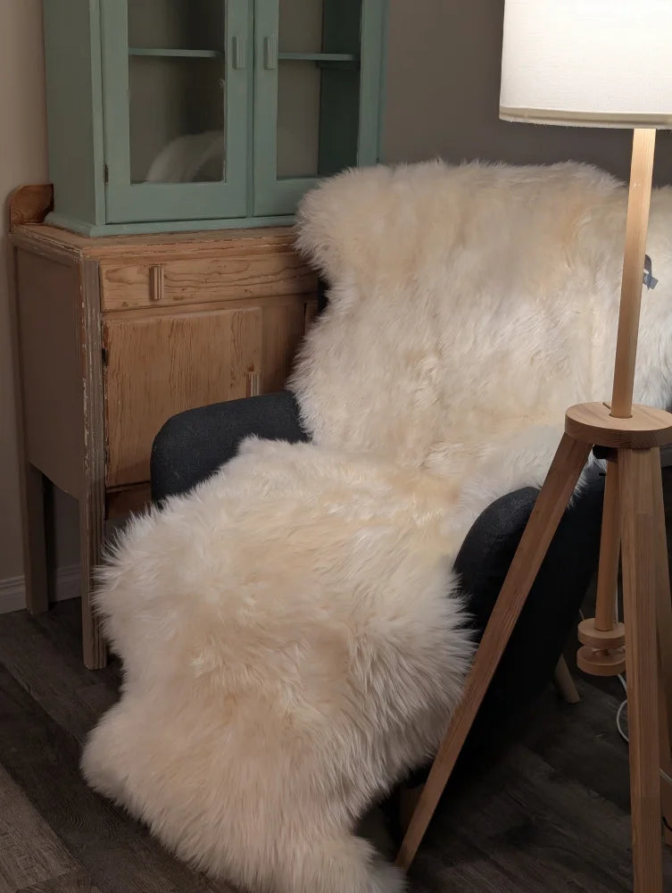 Cream-colored plush double merino sheepskin throw draped over dark armchair oeko tex certified double sheepskin