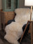 Cream-colored plush double merino sheepskin throw draped over dark armchair oeko tex certified double sheepskin