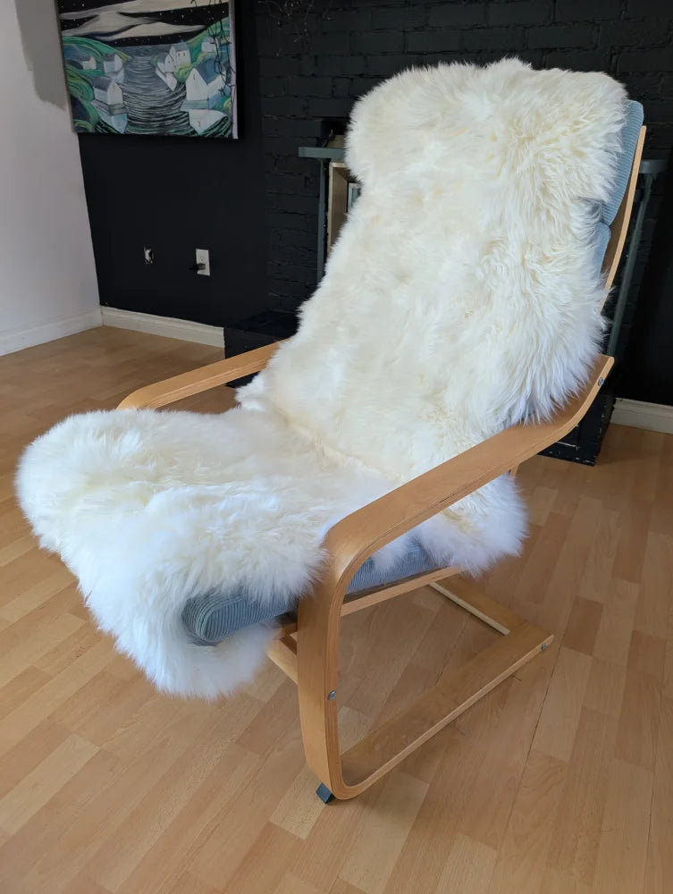 A cozy double soft sheepskin white faux fur throw oeko tex certified draped over a light wood rocking chair with blue cushions