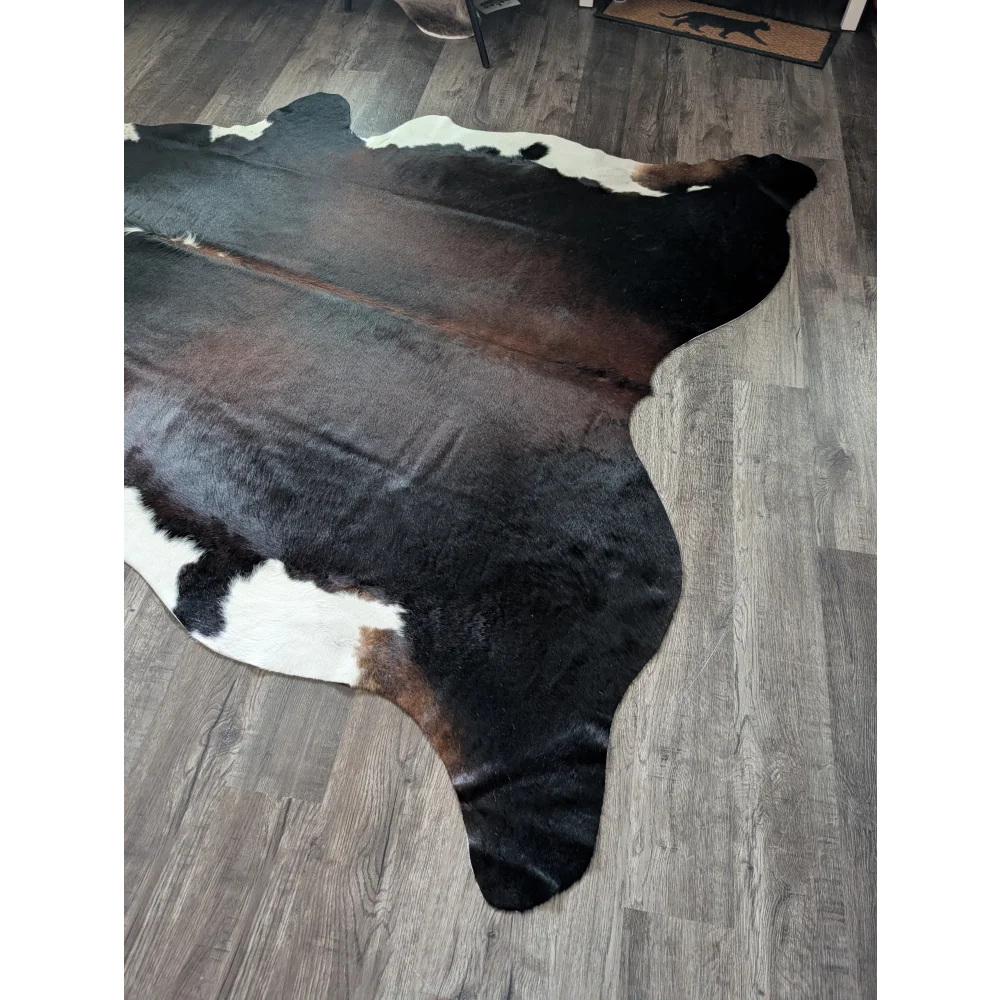 Large cowhide rug in black white and brown with a soft textured surface perfect for beautiful rugs decor