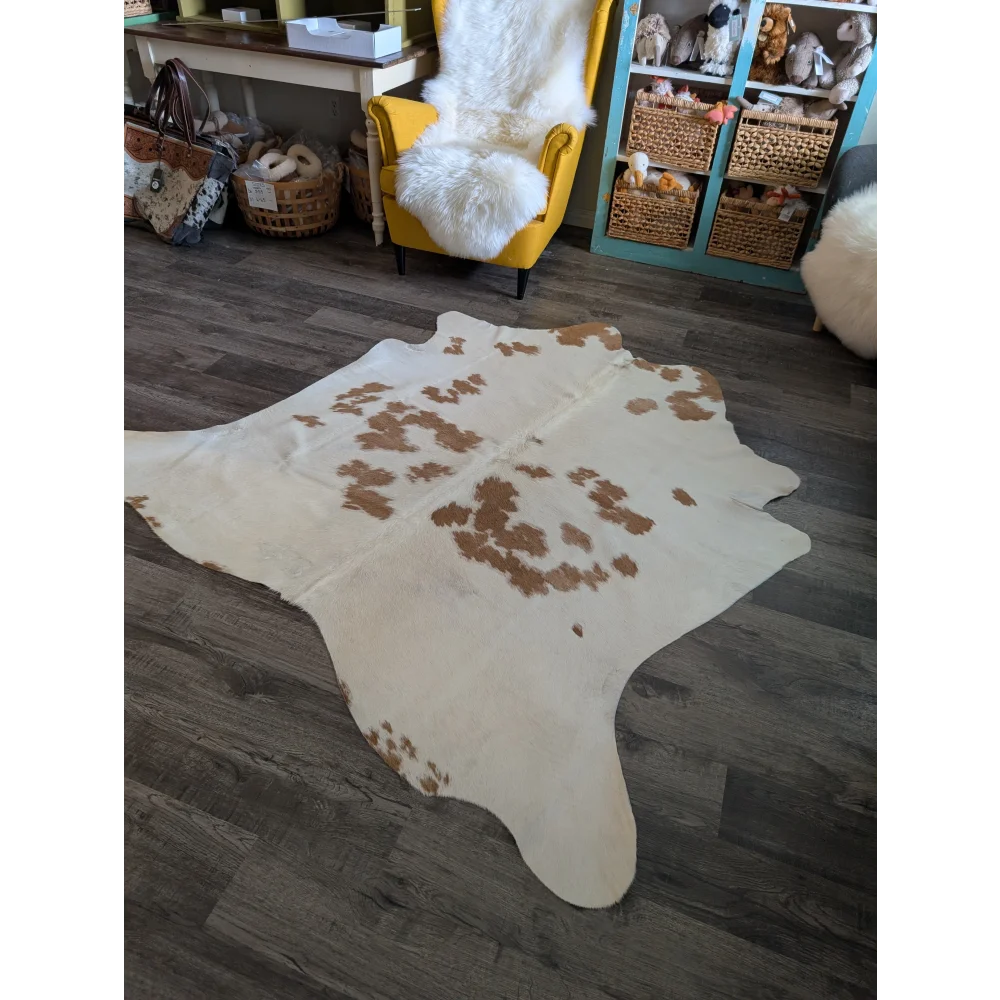 A large cowhide rug with a white base and brown patches in an organic shape perfect for beautiful rugs