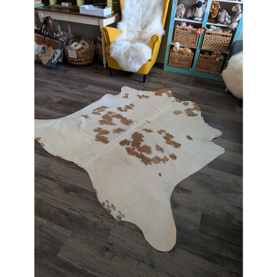 A large cowhide rug with a white base and brown patches in an organic shape perfect for beautiful rugs
