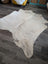 A large cowhide rug es24 in natural white and gray with a soft textured surface, perfect for beautiful rugs collection