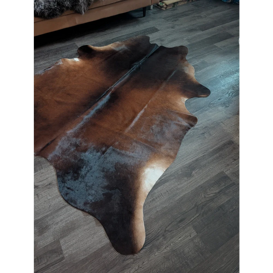 Large cowhide rug with brown and black natural irregular edges featuring unique characteristics for beautiful rugs