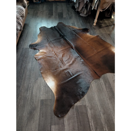 Large cowhide brown and black rug with beautiful irregular edges showcasing unique characteristics and natural charm
