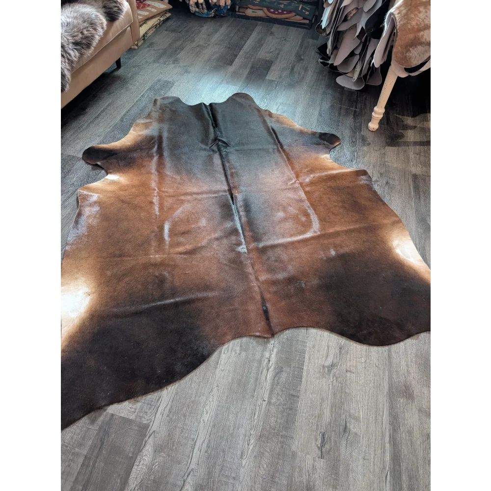Large brown and black cowhide rug with natural irregular edges showcasing unique characteristics for beautiful rugs