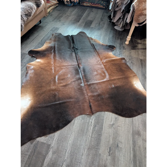 Large brown and black cowhide rug with natural irregular edges showcasing unique characteristics for beautiful rugs