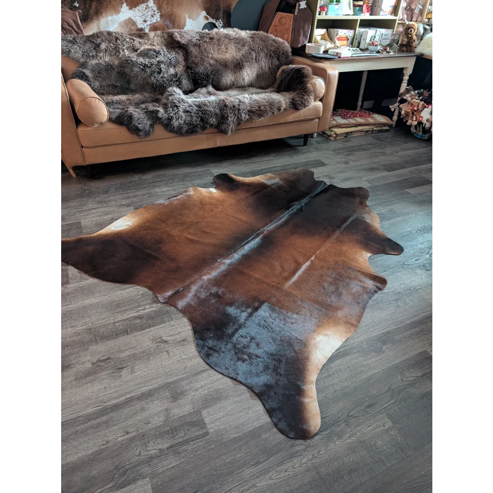 A large brown and black cowhide rug with unique characteristics and a textured unprocessed surface perfect for beautiful rugs