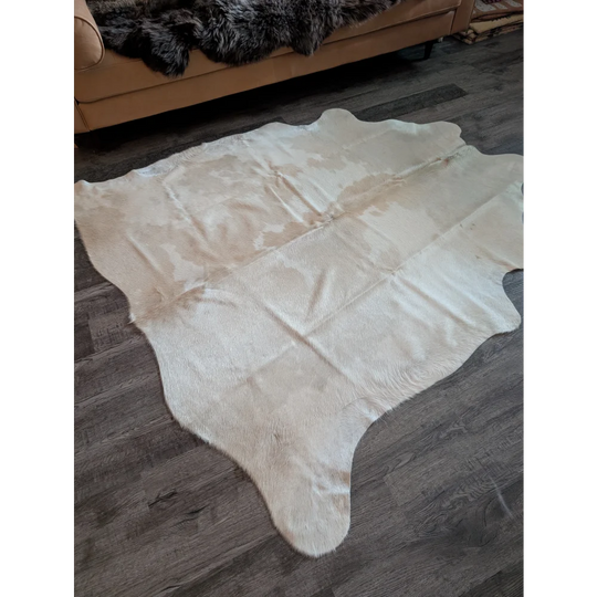 A large cowhide rug in natural white and beige with a soft textured surface perfect for beautiful rugs lovers