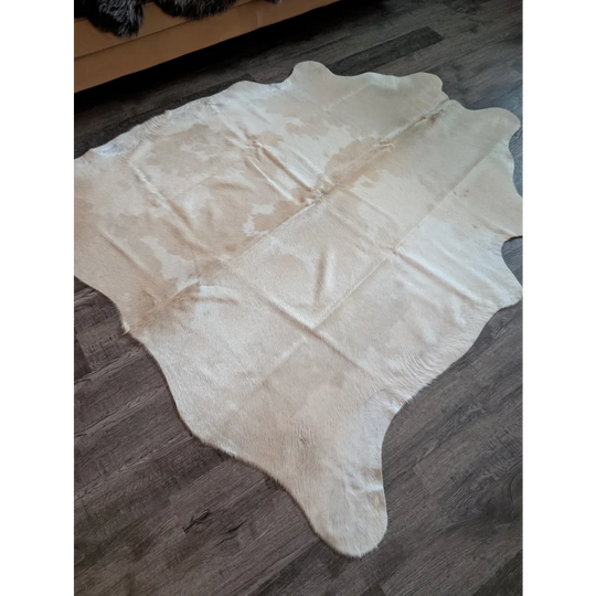 A large natural white and beige cowhide rug with a soft textured surface perfect for beautiful rugs lovers