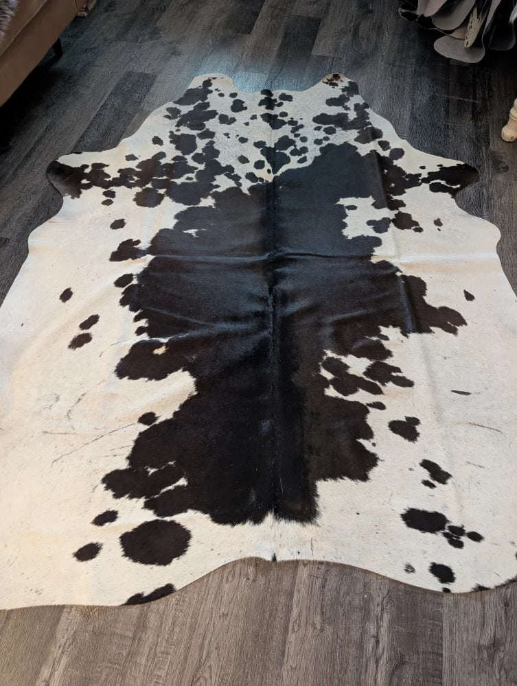 Large cowhide rug es#706 with unique black and white natural patches on a creamy base measuring 78 x 68 inches
