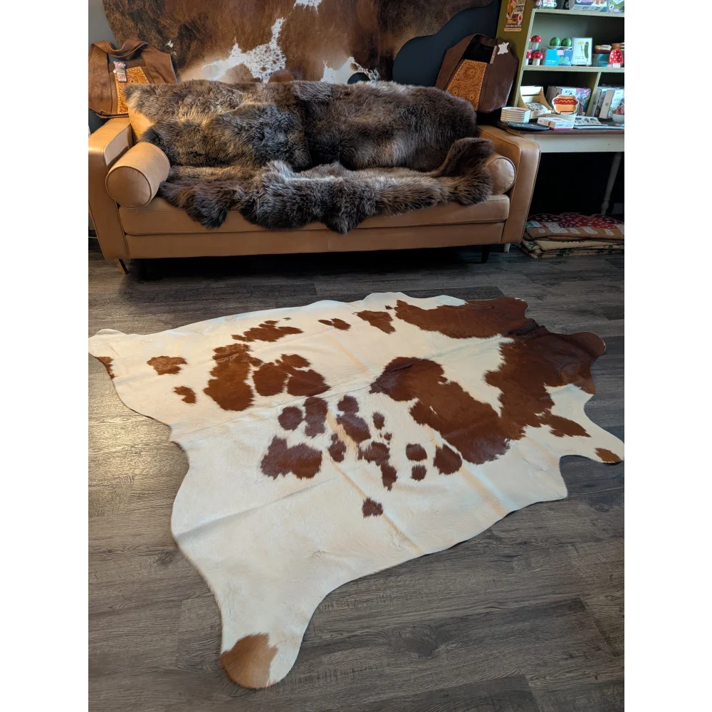 Large cowhide rug with natural brown and white patches showcasing unique characteristics and measuring 81 by 68 inches