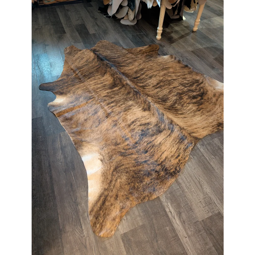 Large cowhide rug in brown and black brindle with natural fur texture showing unique characteristics