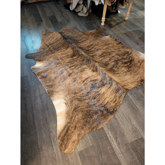 Large cowhide rug in brown and black brindle with natural fur texture showing unique characteristics