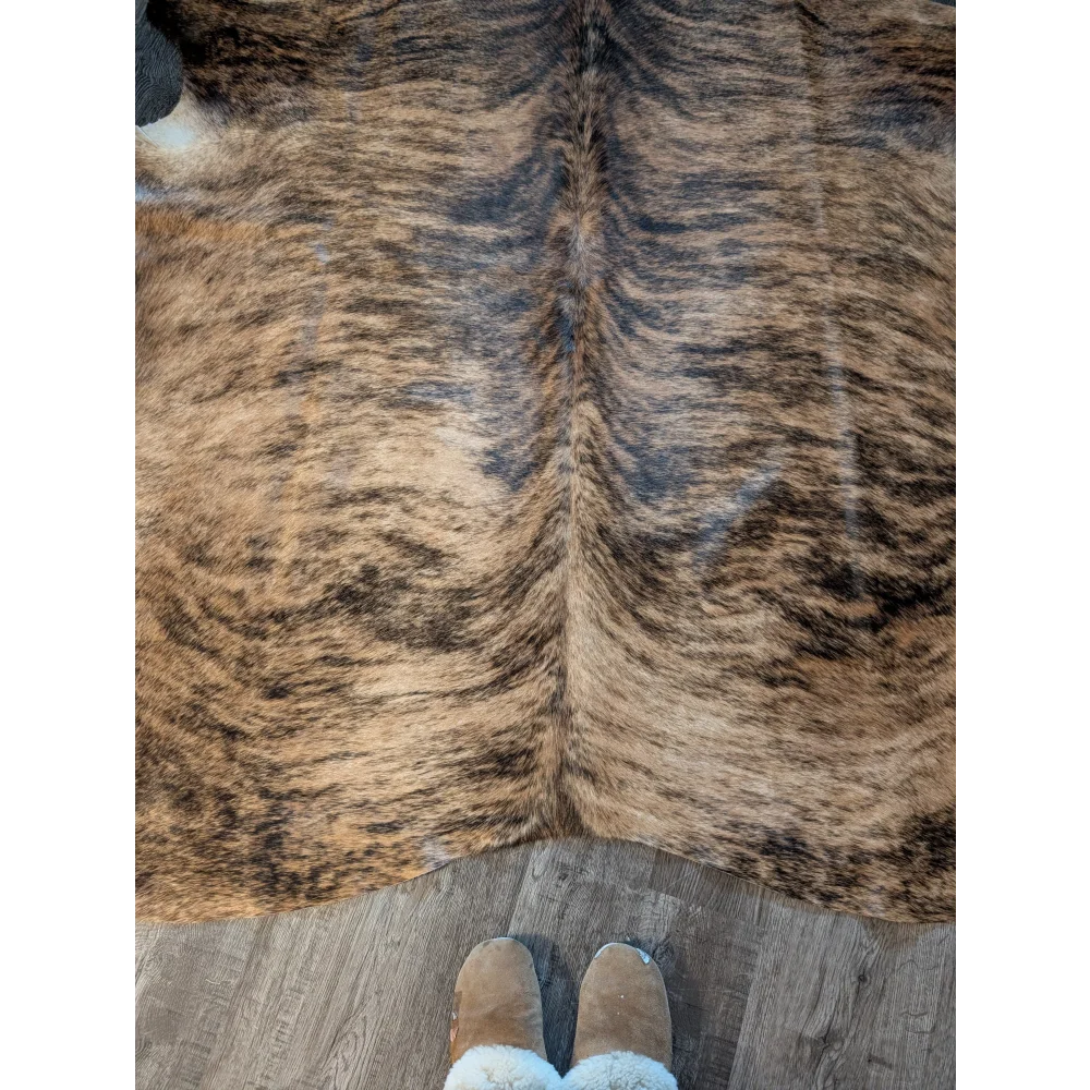 Large brown and black brindle cowhide rug with natural textured fur and unique characteristics perfect for decor