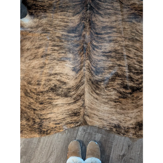 Large brown and black brindle cowhide rug with natural textured fur and unique characteristics perfect for decor