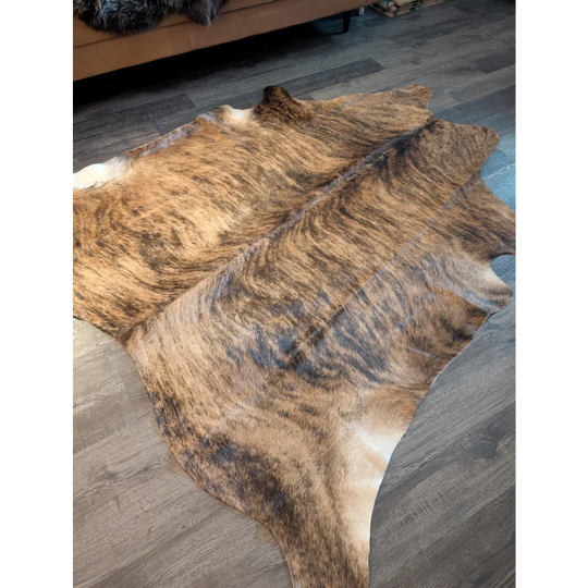 Large cowhide rug es716 with natural brown and black brindle unique characteristics on gray wood floor