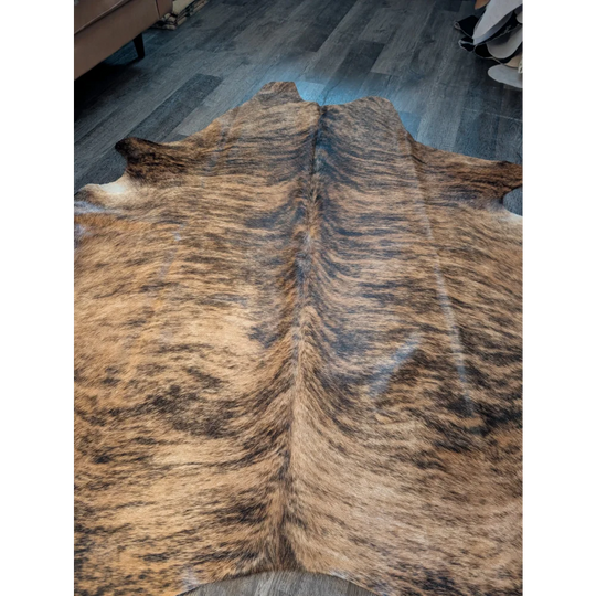 Large brown and black striped cowhide rug with unique characteristics and a textured furry surface perfect for any space