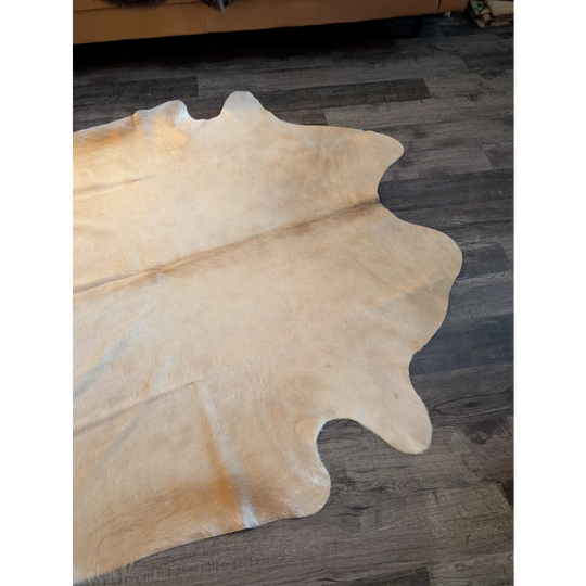 Natural tan large cowhide rug with soft textured surface and unique irregular edges perfect for any room