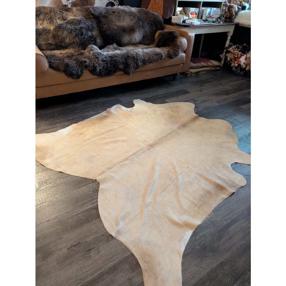 Natural tan large cowhide rug with smooth textured surface and unique irregular edges perfect for stylish decor