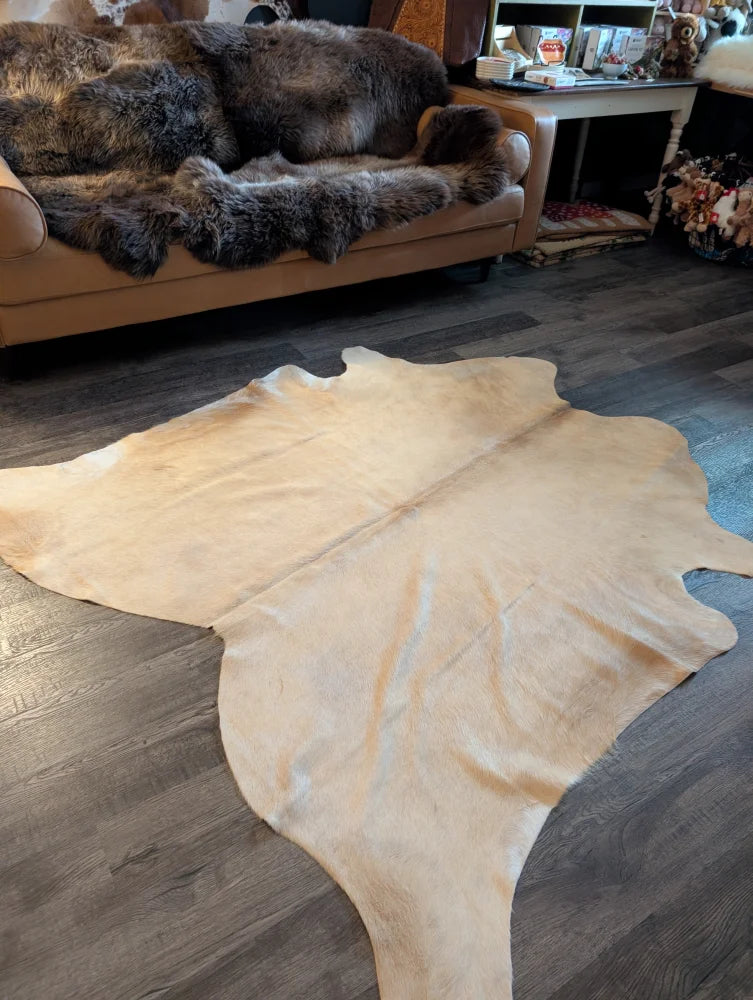 Natural tan large cowhide rug with smooth textured surface and unique irregular edges perfect for stylish decor
