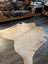 Natural tan large cowhide rug with smooth textured surface and unique irregular edges perfect for stylish decor