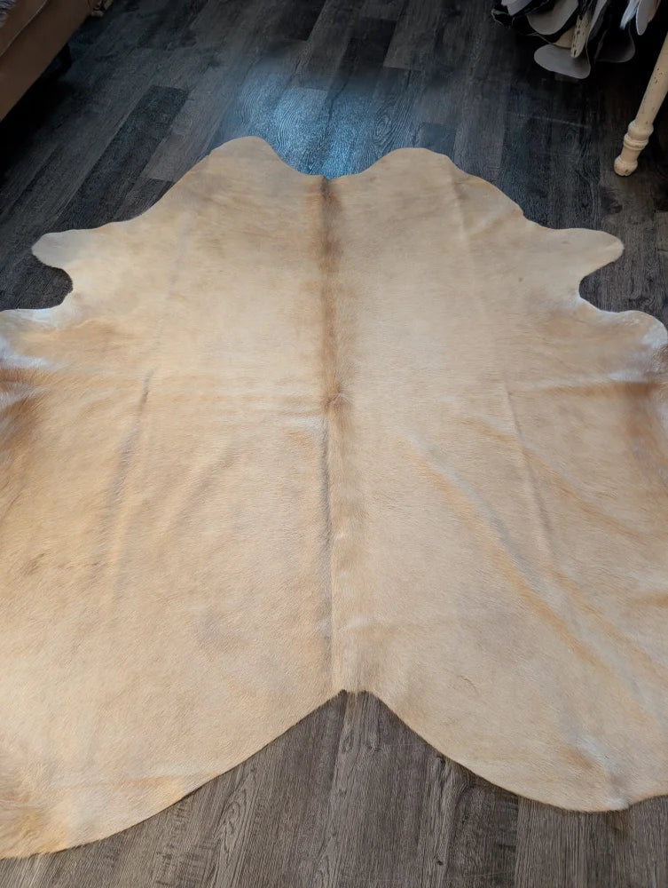Beige large cowhide rug with natural fur texture and unique irregular edges perfect for stylish decor