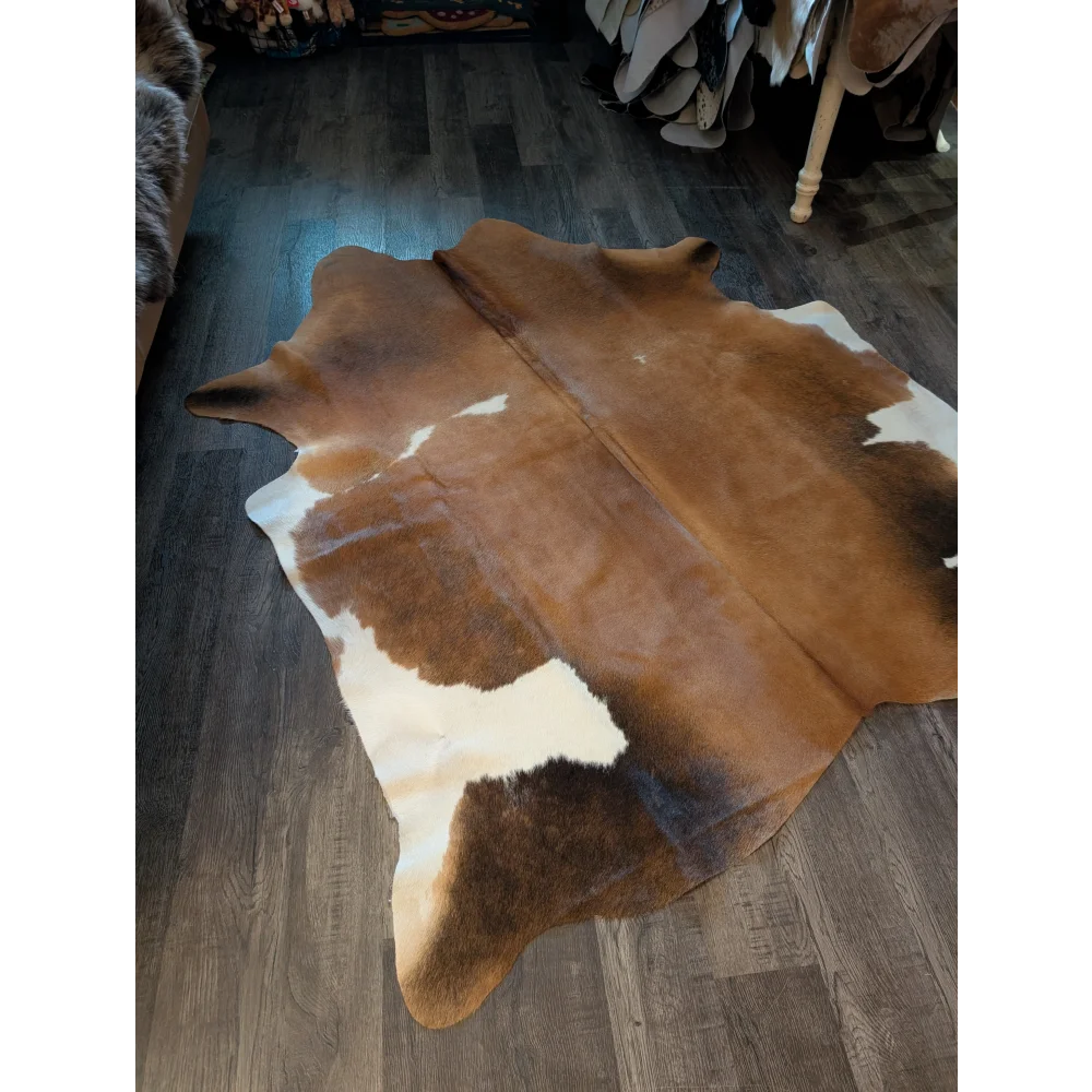 Large brown and white cowhide rug with natural fur texture showcasing unique characteristics in 78 x 67 size