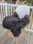 Black icelandic sheepskin chair throw draped over modern white chair with wooden legs perfect as extra large chair pads
