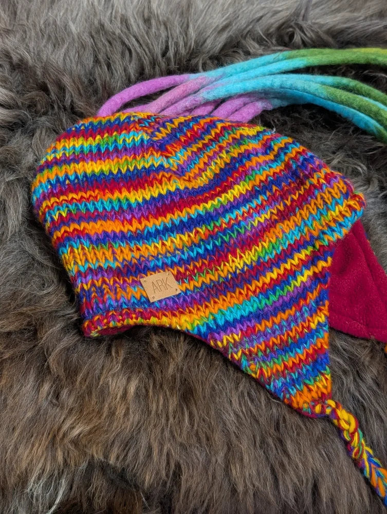 Colorful knitted rainbow rasta hat with earflaps and braided ties for a fun look