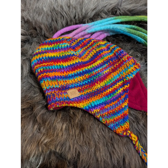 Colorful knitted rainbow rasta hat with earflaps and braided ties for a fun look