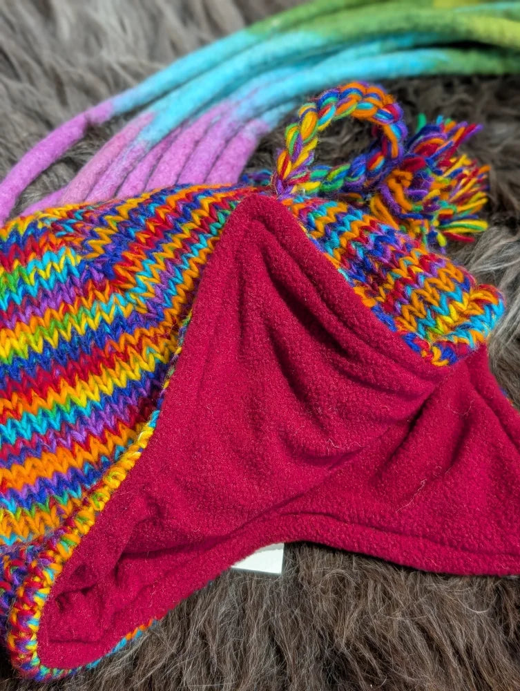 Rainbow rasta hat with colorful stripes, red fleece lining, and pom-pom for winter warmth
