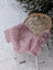 A soft fluffy pink merino sheepskin rug draped over a wicker chair meeting reach standards