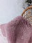 A soft plush lavender pink merino sheepskin throw draped over a wicker chair meets reach standards