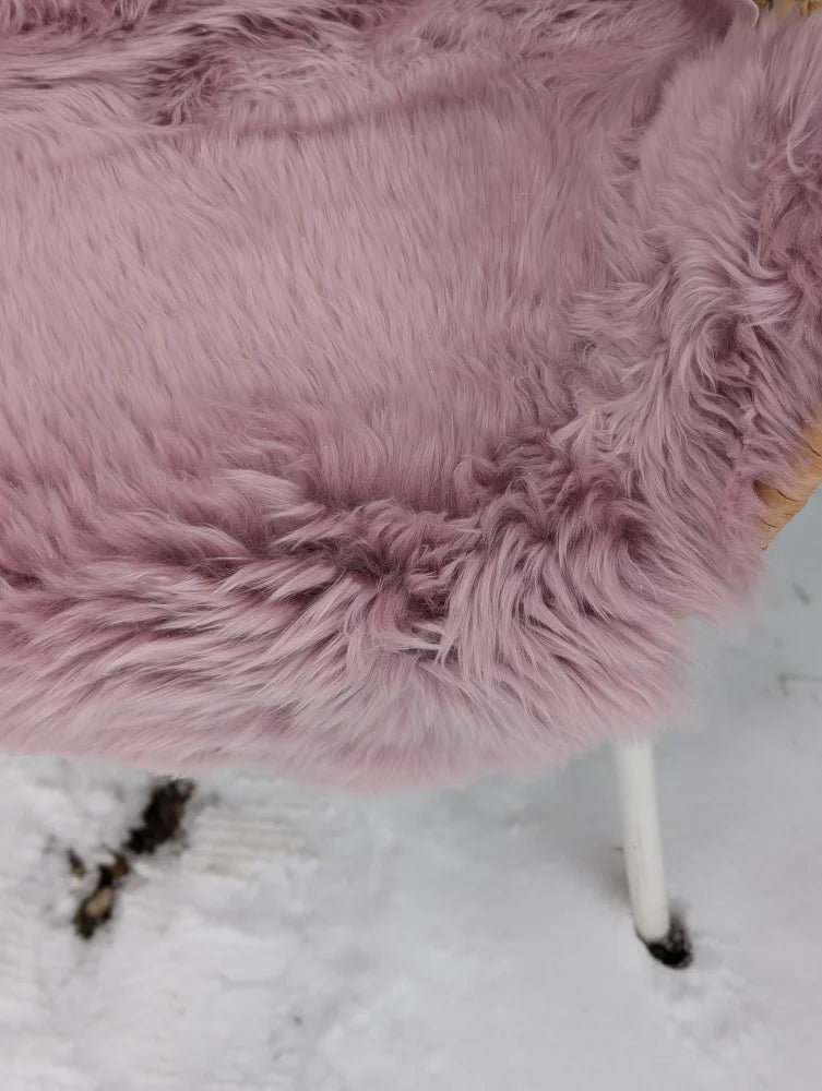 A soft pink merino sheepskin throw draped over a chair meets reach standards for cozy decor
