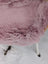 A soft pink merino sheepskin throw draped over a chair meets reach standards for cozy decor