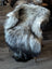 A plush long wool icelandic sheepskin rug in natural grey draped over a white wooden chair backrest