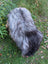 A shaggy long wool icelandic dog with gray and black fur standing on grass next to a fall#1 massive icelandic natural grey sheepskin