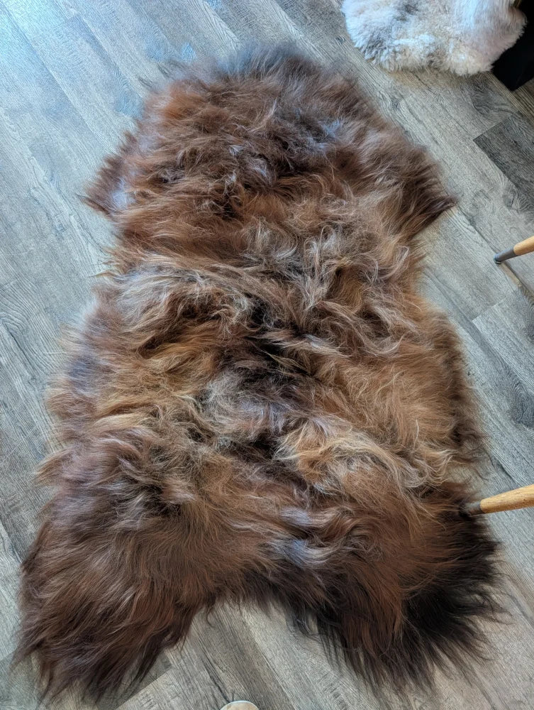A plush naturally textured brown icelandic sheepskin rug with soft shaggy fur in dark rusty wool icelandic style