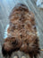 A plush icelandic sheepskin rug in natural dark rusty brown and creamy white wool icelandic texture measuring 58 by 33 inches