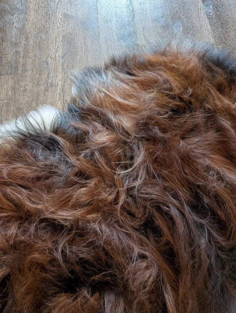A massive 57 by 40 inch brown and gray shaggy faux fur rug resembling soft wool icelandic sheepskin material