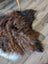 A plush irregular brown and black icelandic sheepskin rug with white border on wooden floor perfect for cozy decor