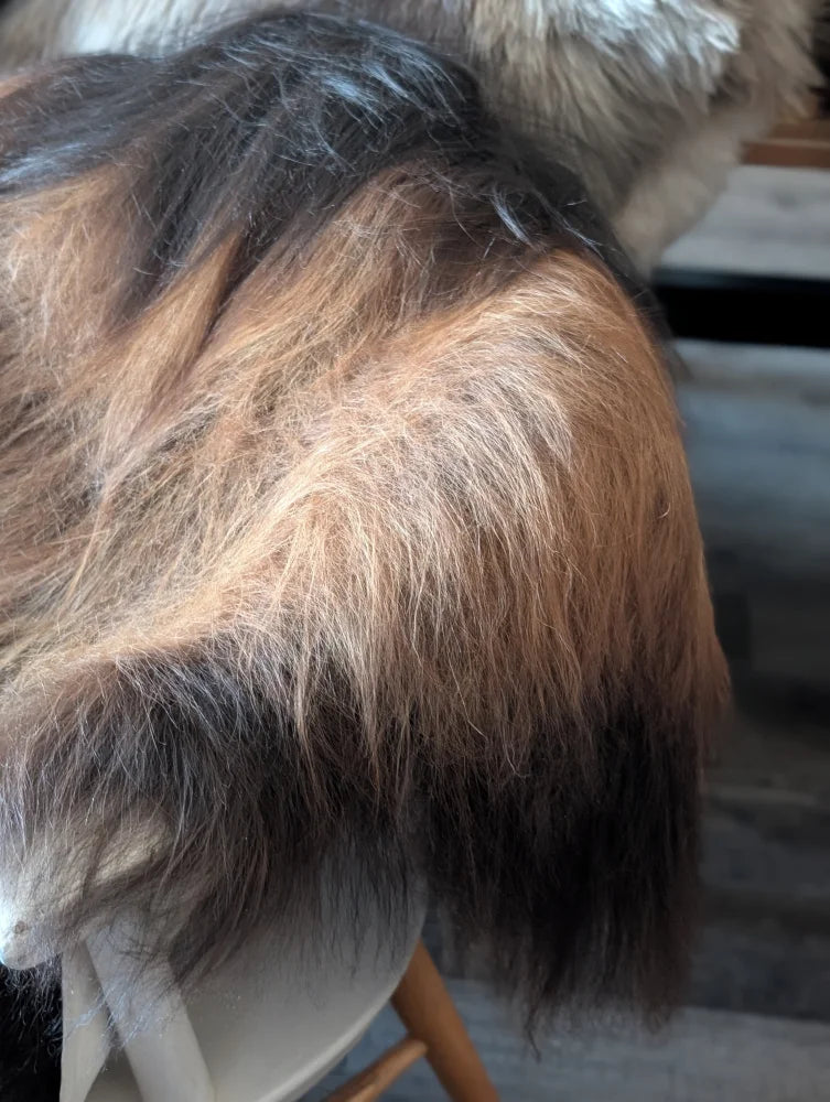 A fluffy gradient-colored wig with dark roots and blonde strands paired with a massive natural dark rusty icelandic sheepskin