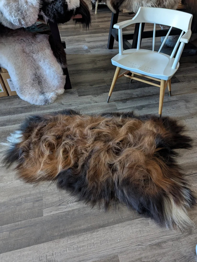 A plush irregular icelandic sheepskin rug in natural dark rusty brown and black wool icelandic fur measuring 59 x 33 inches