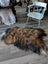A plush irregular icelandic sheepskin rug in natural dark rusty brown and black wool icelandic fur measuring 59 x 33 inches
