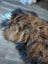 A plush multicolored icelandic sheepskin rug in brown black and white wool icelandic fur on a wooden floor
